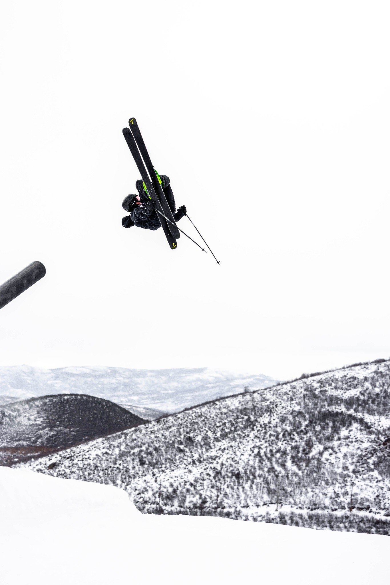 Jamison midair on skis above snowy mountains